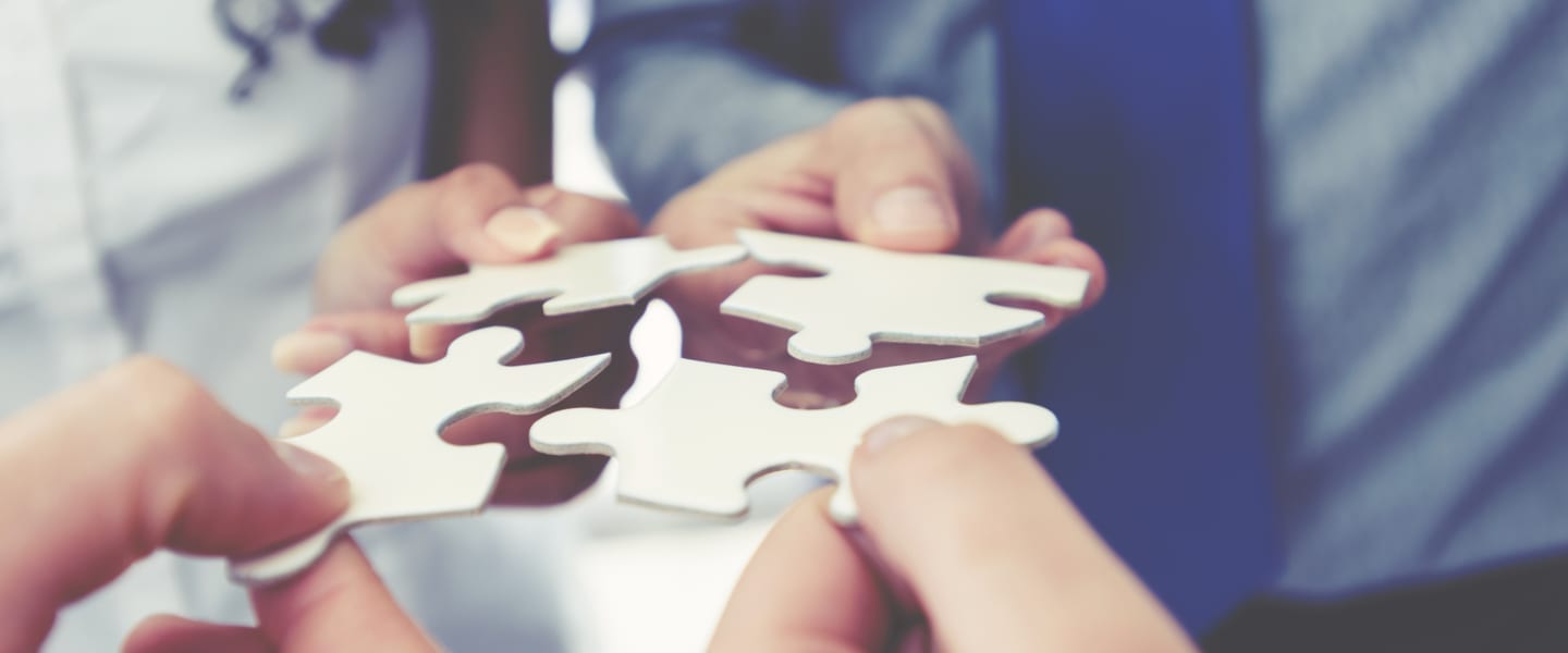 group of people holding puzzle pieces together