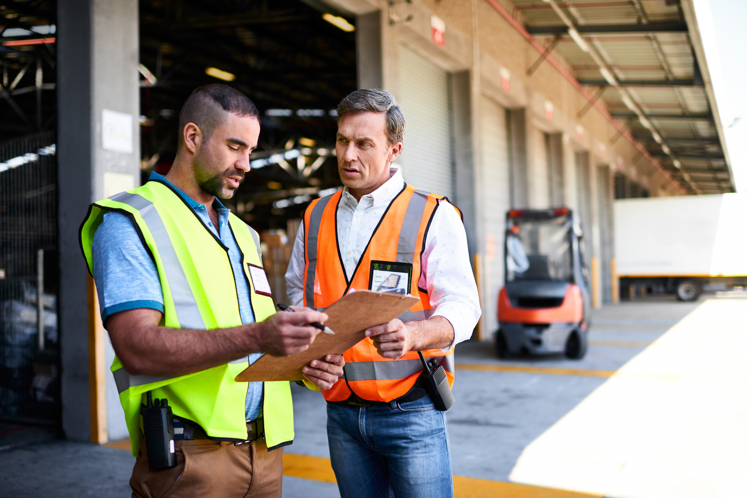 Warehouse workers checking clipboard at loading bay