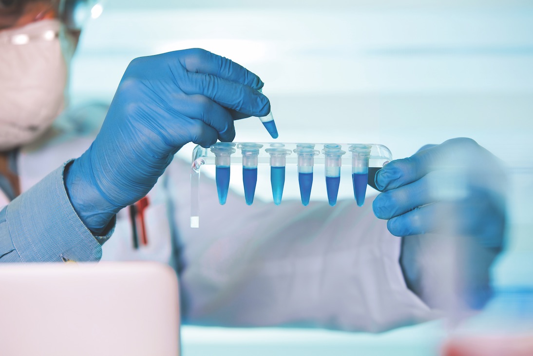 Scientist holding blue samples in test tubes in a lab